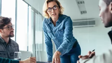 Kobieta rozmawia ze swoimi kolegami z pracy w nowoczesnym biurze