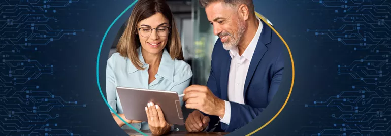 A woman in formal attire holds a tablet while a man in a suit and shirt uses a stylus to sign a document on the tablet’s screen.